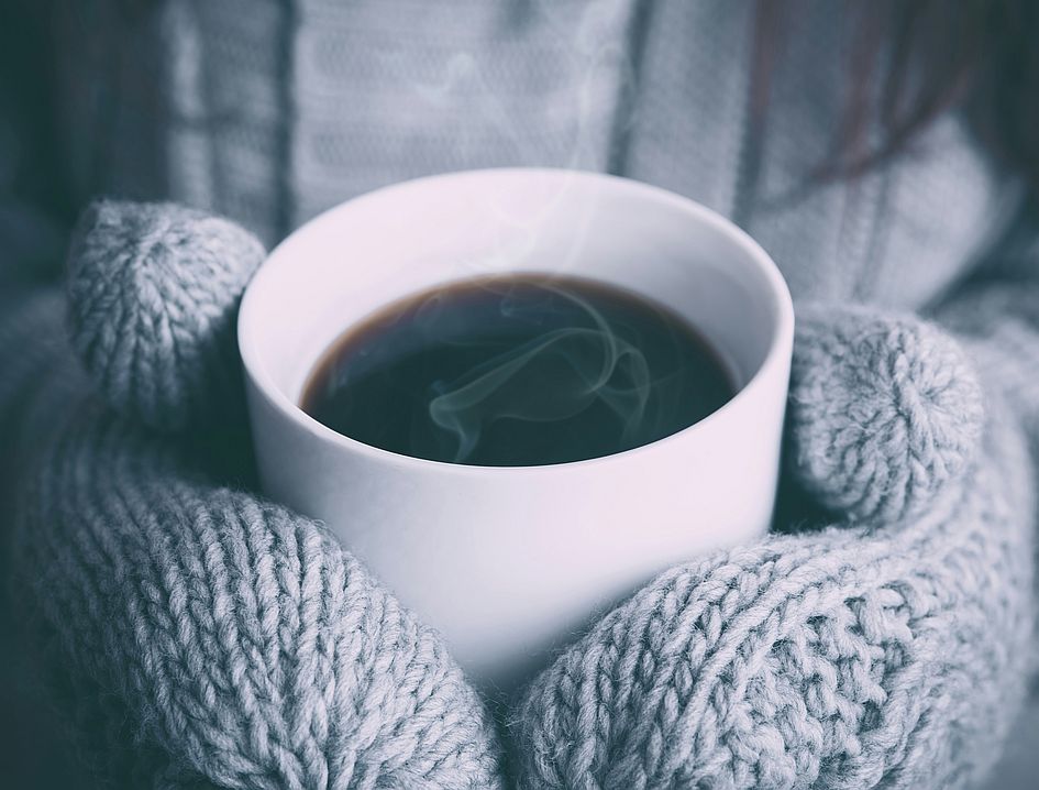 Picture of hands in mitts holding a coffee
